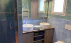 Blaues Badezimmer mit zwei Wasserhähnen und begehbarer Dusche